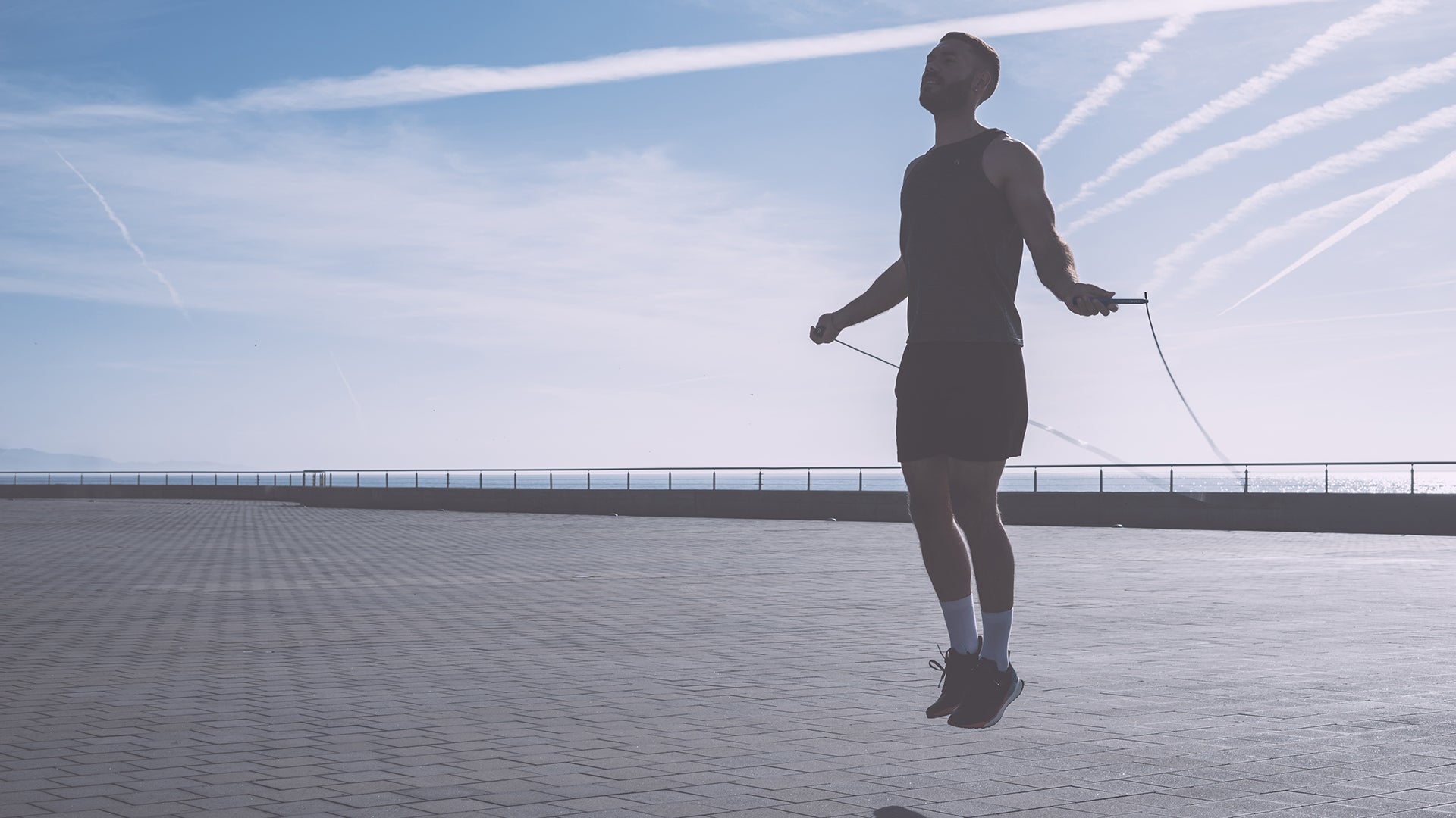 Image of healthy male being active using a PurposeBuilt jump rope on a sunny day in front of the sea.